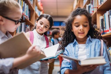 schoolgirls looking for books in library clipart