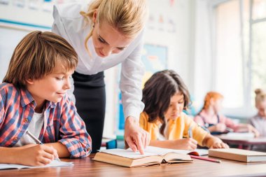 teacher helping schoolboy with exercise clipart