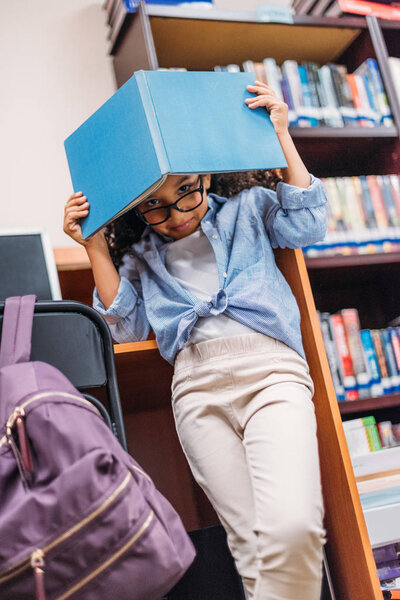 schoolgirl covering head with book