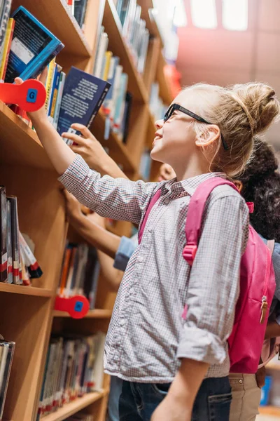 Schoolmeisjes kiezen van boeken in bibliotheek — Stockfoto