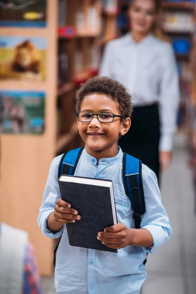 Мальчик в библиотеке с учителем — стоковое фото