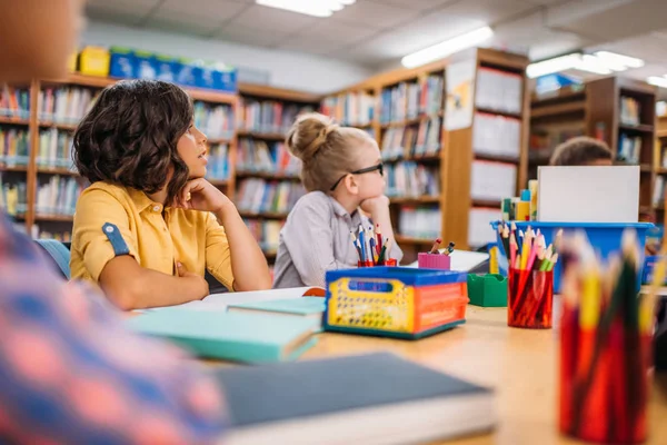 Niños sentados en el escritorio en la biblioteca — Foto de Stock