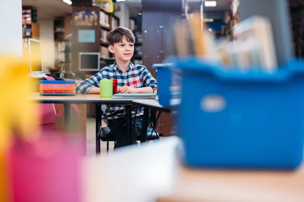 Schoolboy sitting in library — Stock Photo, Image