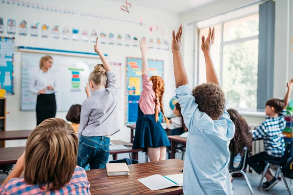 Bambini che alzano le mani in classe — Foto Stock