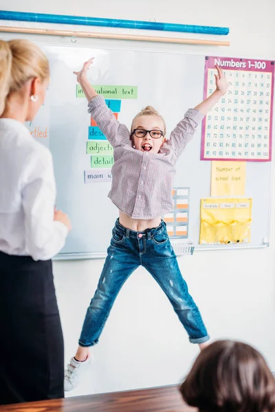 Teacher looking at jumping schoolgirl — Free Stock Photo
