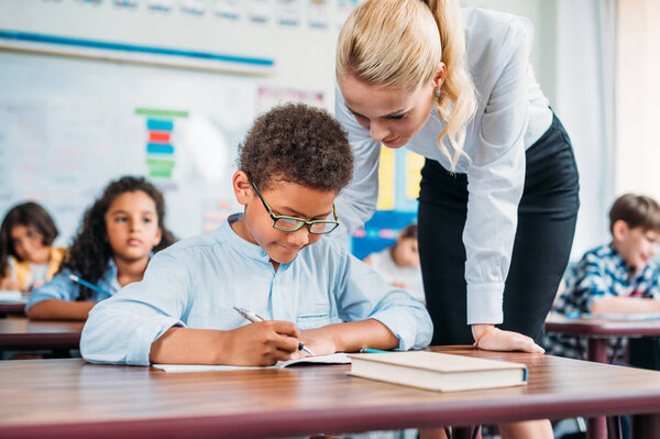 teacher helping schoolboy with exercise