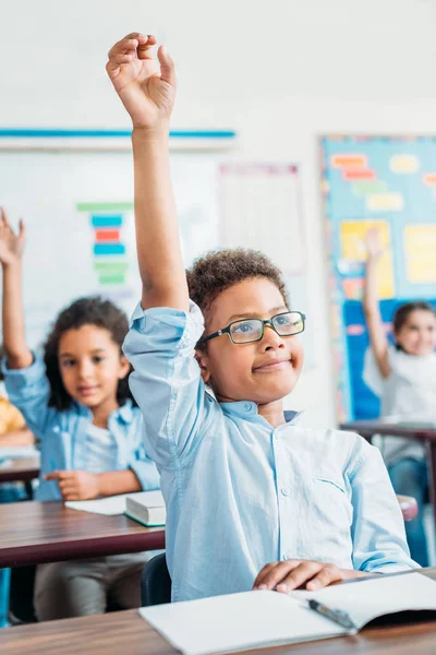 Crianças levantando as mãos na classe — Fotografia de Stock