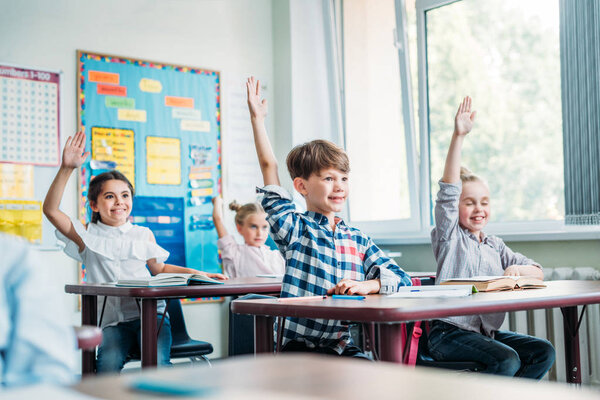 дети поднимают руки в классе
