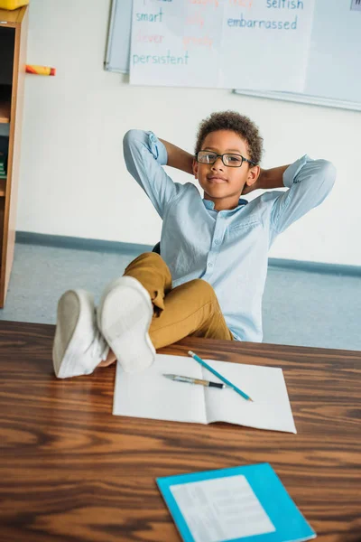 Schoolboy sitting with feet on table — Stock Photo, Image