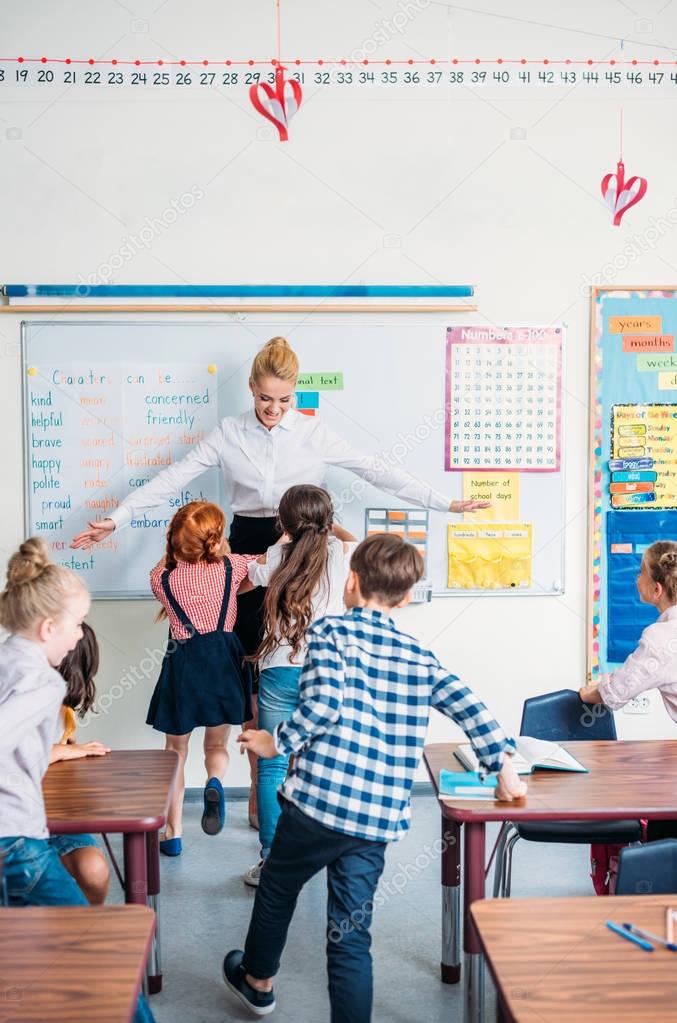 teacher embracing with pupils