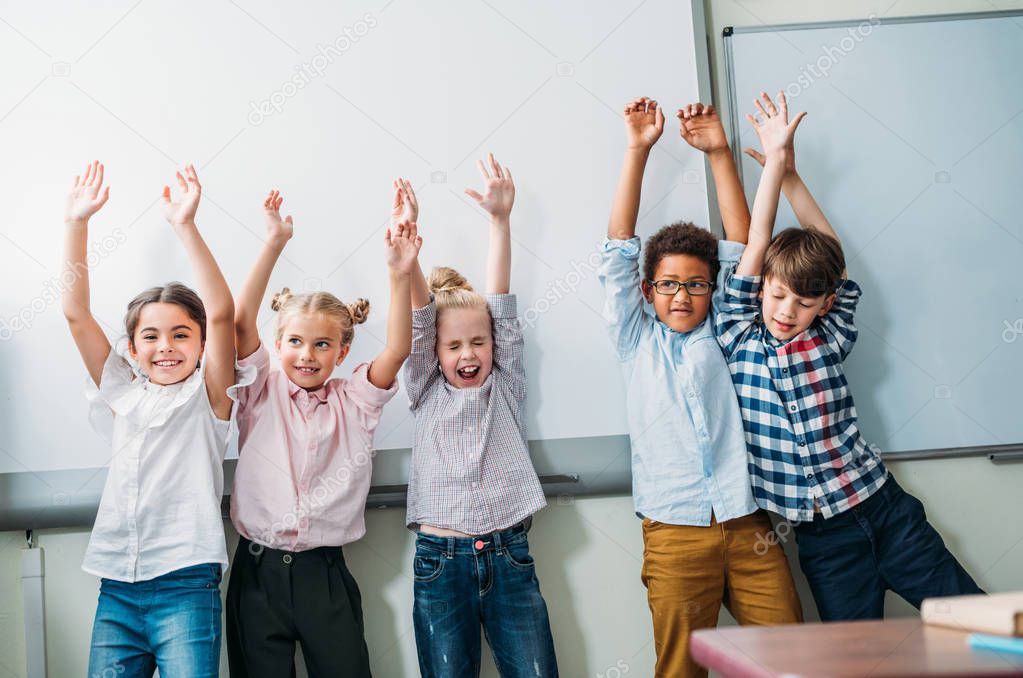 kids with raised hands next to whiteboard