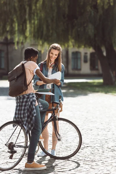 Pareja multiétnica con libros y bicicleta — Foto de Stock