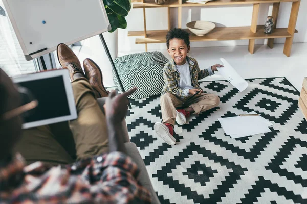 Boy drawing while father using tablet — Stock Photo, Image