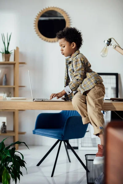 Ragazzo seduto sul tavolo e utilizzando il computer portatile — Foto Stock