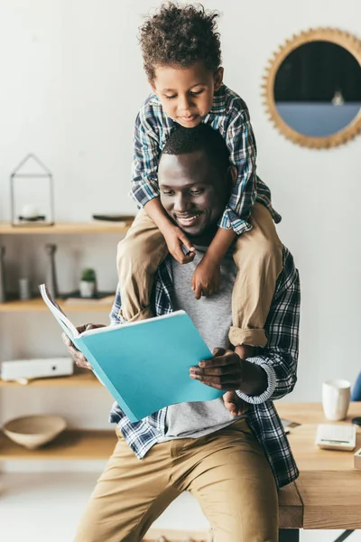 Figlio piggybacking sul padre di lavoro — Foto Stock