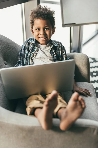 Pojke med laptop i fåtölj — Stockfoto