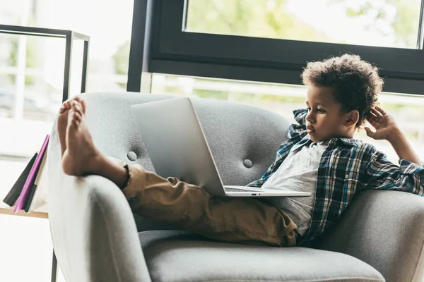 Menino com laptop em poltrona — Fotografia de Stock