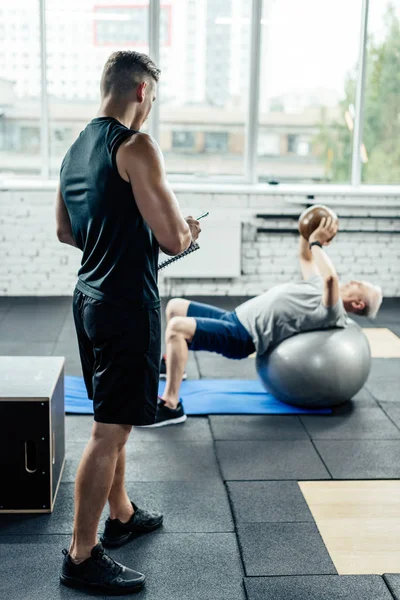 Trainer looking on senior sportsman — Free Stock Photo