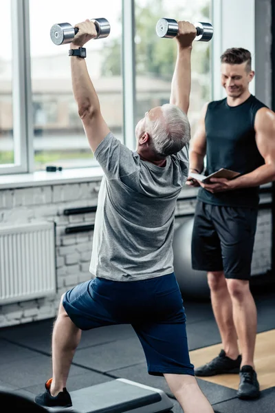 Sportsman doing lunges with dumbbells — Stock Photo, Image