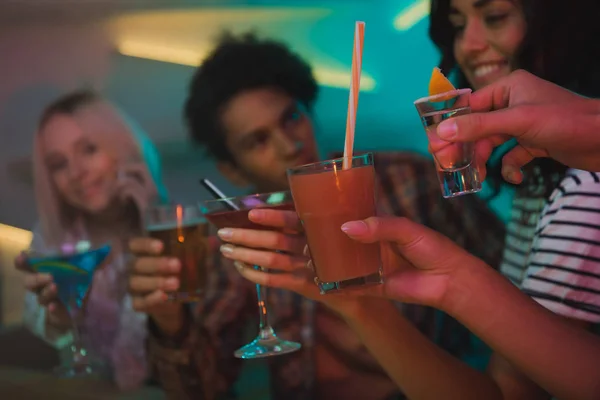 Multiethnic friends clinking cocktails in bar