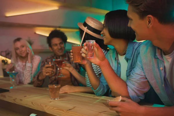 Amigos multiétnicos bebendo coquetéis no bar — Fotografia de Stock