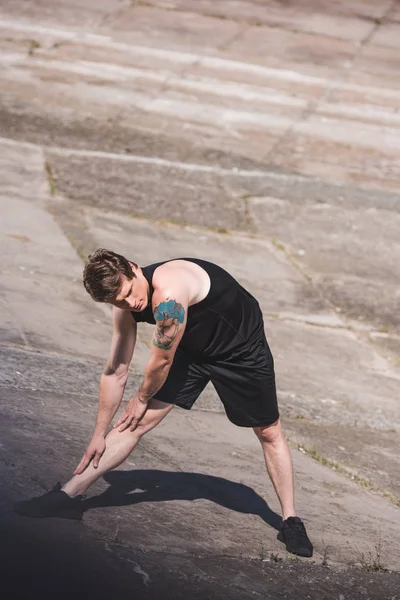 Man stretching on slabs — Free Stock Photo