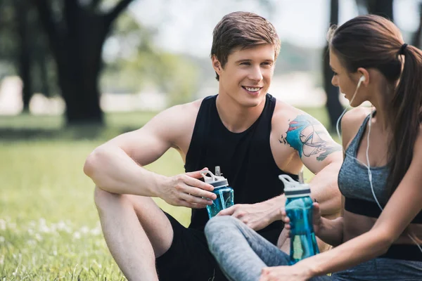 Sportive couple resting in park — Stock Photo, Image