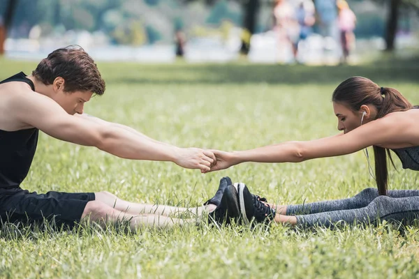 Couple stretching in park — Stock Photo, Image
