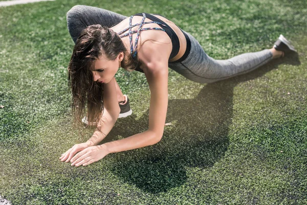 Woman stretching on sports field — Free Stock Photo