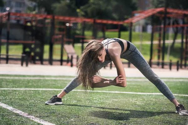 Femeia se întinde pe terenul sportiv — Fotografie de stoc gratuită