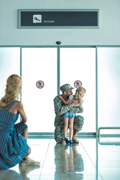 Criança abraçando pai em uniforme militar — Fotografia de Stock