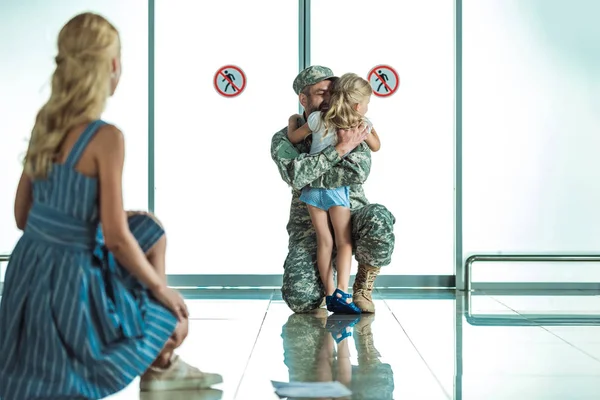 Criança abraçando pai em uniforme militar — Fotografia de Stock