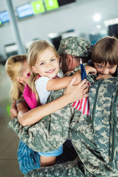 Сім'я обіймає батька в аеропорту — стокове фото