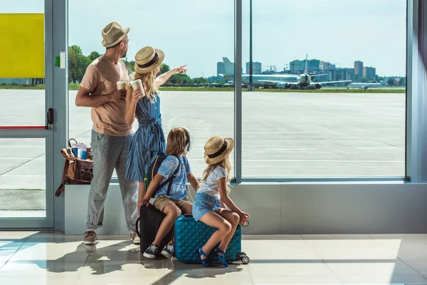 Familie kijkt uit raam in luchthaven — Stockfoto