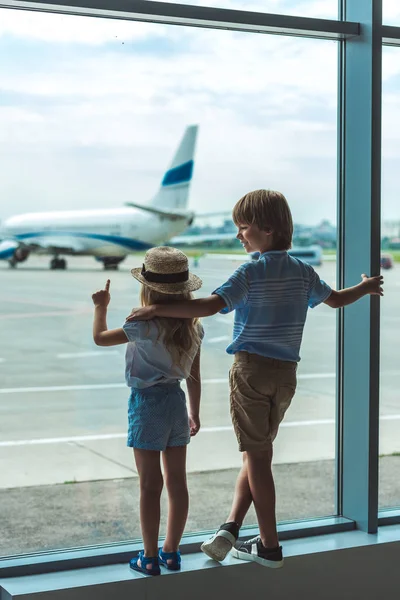 Дети смотрят в окно в аэропорту — стоковое фото