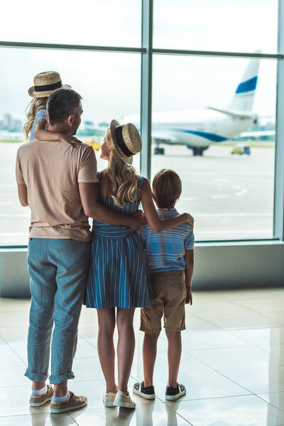 семья, выглядывающая из окна в аэропорту
