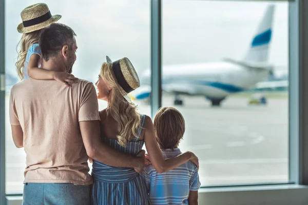 Familie kijkt uit raam in luchthaven — Stockfoto