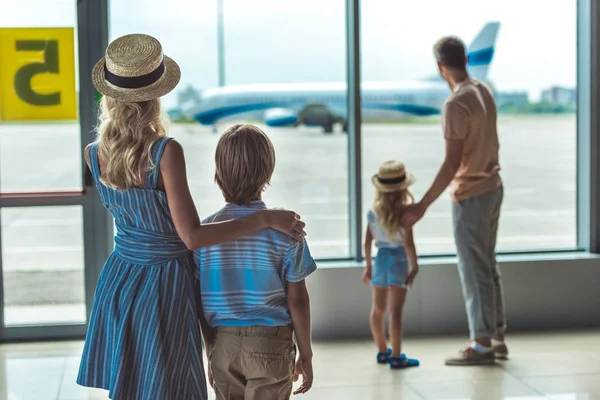 Familie kijkt uit raam in luchthaven — Stockfoto