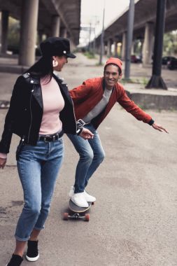 man riding to girlfriend on skateboard clipart