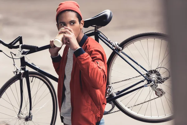 Чоловік з велосипедом п'є каву, щоб піти — стокове фото