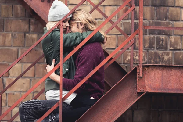 Casal sentado nas escadas e abraçando — Fotografia de Stock