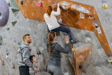 Little girl climbing wall with grips clipart