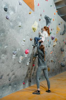 Little girl climbing wall with grips clipart