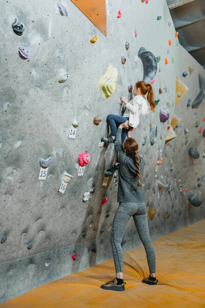 Little girl climbing wall with grips