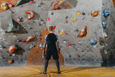 young man in front of climbing wall clipart