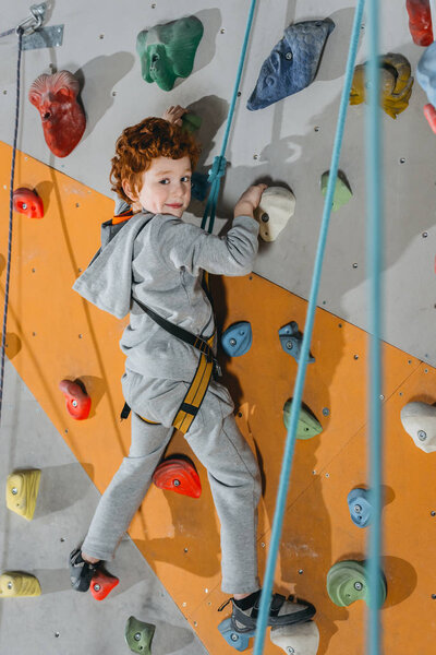 Little boy climbing wall with grips
