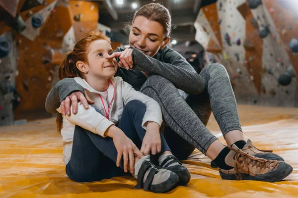 Tjej och mamma kramas på matta på gym — Stockfoto