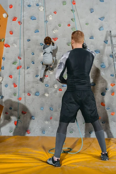Pequeño niño escalando pared con agarres — Foto de stock gratis