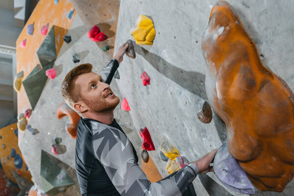 Man climbing wall with grips