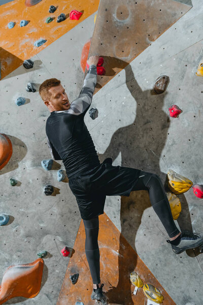 Man climbing wall with grips